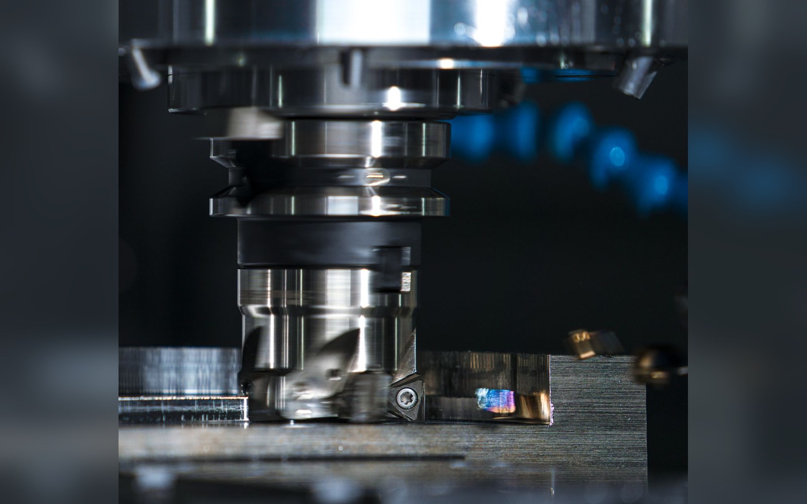 Small factory floor with aluminium CNC-cut binding components in a parts bin, a machining centre visible in the background