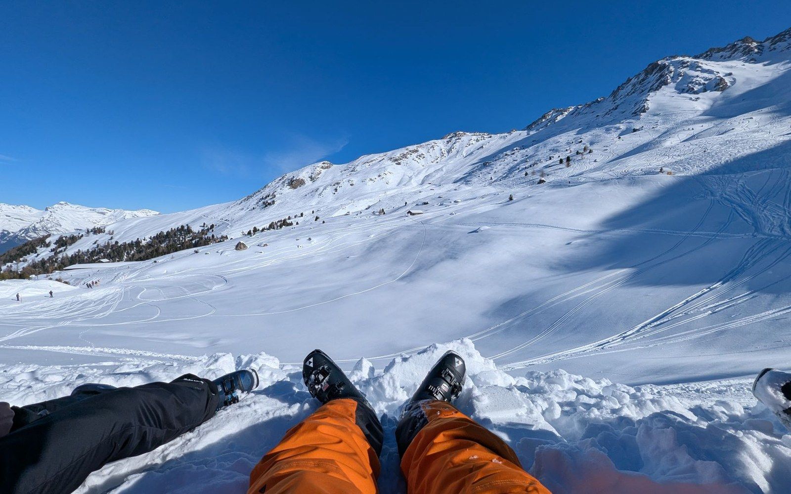 Snowboard boots stretched out on a snowy slope beneath a bright blue sky