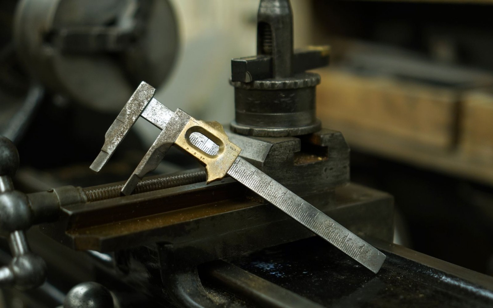 An old vernier caliper resting on a metal lathe's tool carriage