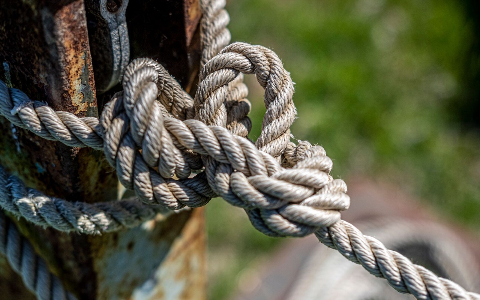 Thick rope tied in a knot around a rusted metal post